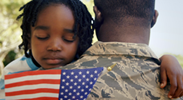 A U.S. veteran hugging his daughter while she holds a mini United States flag